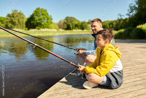 happy smiling father and son fishing on river