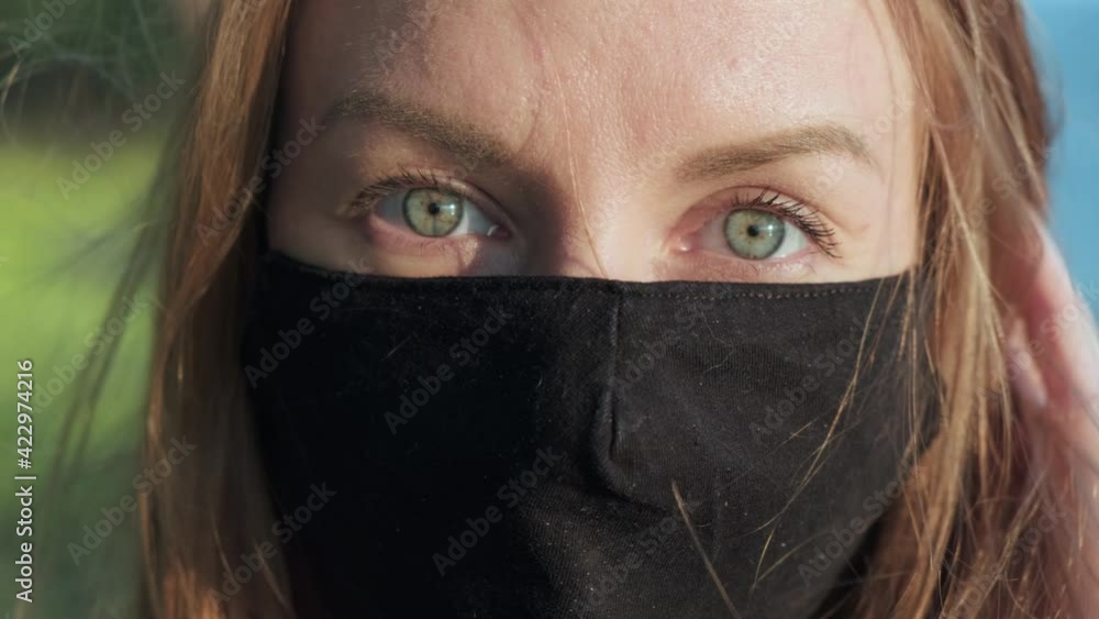 Smiling attractive woman with green eyes taking off face mask Smiling attractive woman with green eyes taking off face mask