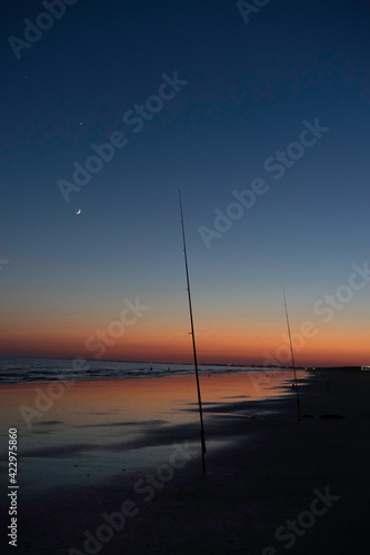 Night photography of a fishing rod on the beach. In the sky the conjunction of jupiter, venus and the moon