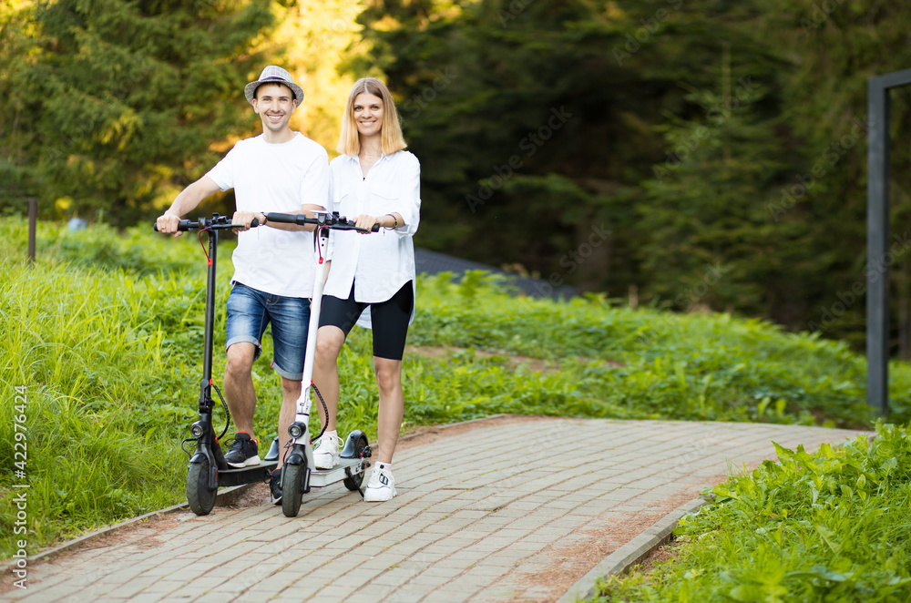 Happy modern couple of man and woman enjoying eco ride by electric scooter  in sunny day on vacation. Having fun together driving electric scooter  through city centre. Stock Photo | Adobe Stock
