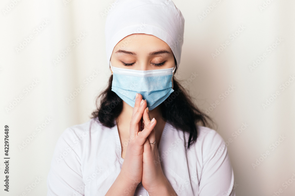 Nurse young medic closed eyes pray for patients health. Female doctor dressed in medical gown and surgical hat. Pandemic virus coronavirus concept, disposable face mask, copy space.
Nurse young medic closed eyes pray for patients health. Female doctor dressed in medical gown and surgical hat. Pandemic virus coronavirus concept, disposable face mask, copy space.
