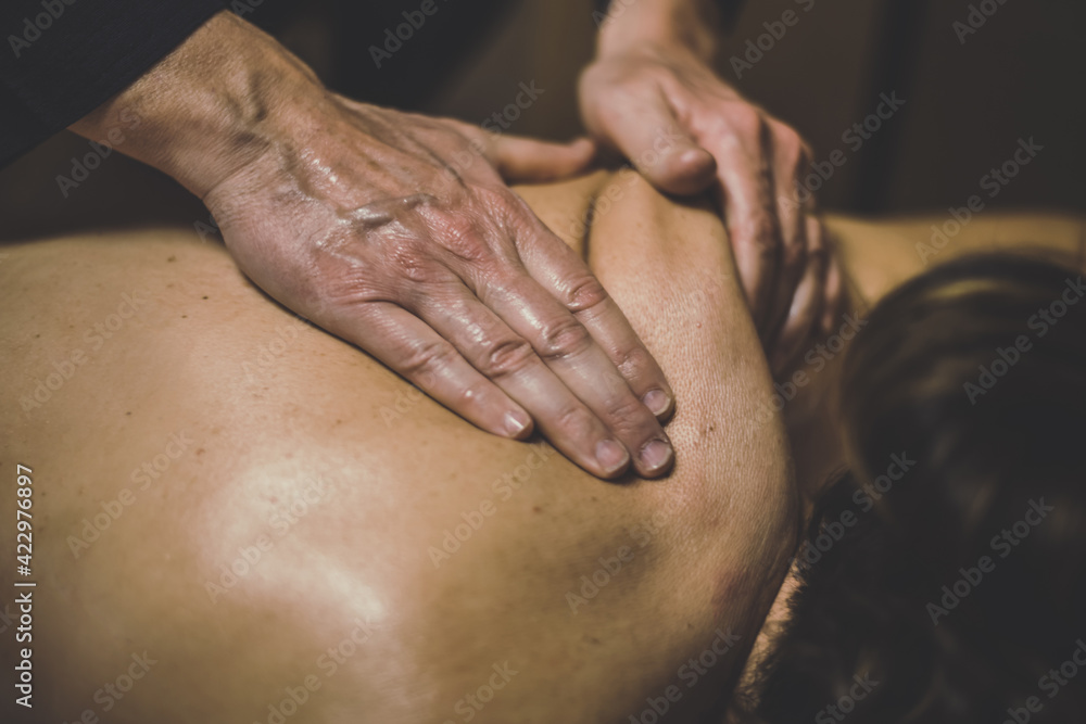 Fototapeta premium Soft focus view of man massaging a woman in a wellness center Oiled hands on a body relaxing the muscles and relieve tension .Holistic exercise for calm and clear your mind. Health well-being concept