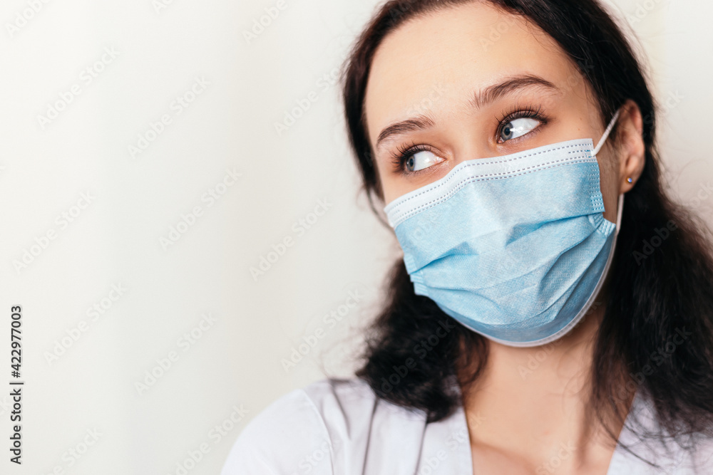 Nurse young medic looking aside. Female doctor dressed in medical gown and surgical face blue mask. Image with copy space. Pandemic virus coronavirus concept
Nurse young medic looking aside. Female doctor dressed in medical gown and surgical face blue mask. Image with copy space. Pandemic virus coronavirus concept