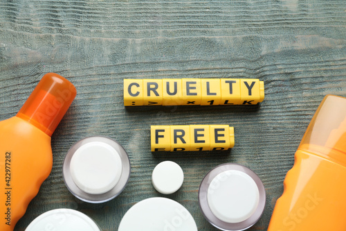 Fototapeta Naklejka Na Ścianę i Meble -  Flat lay composition with words Cruelty Free and different cosmetic products not tested on animals against light blue wooden background