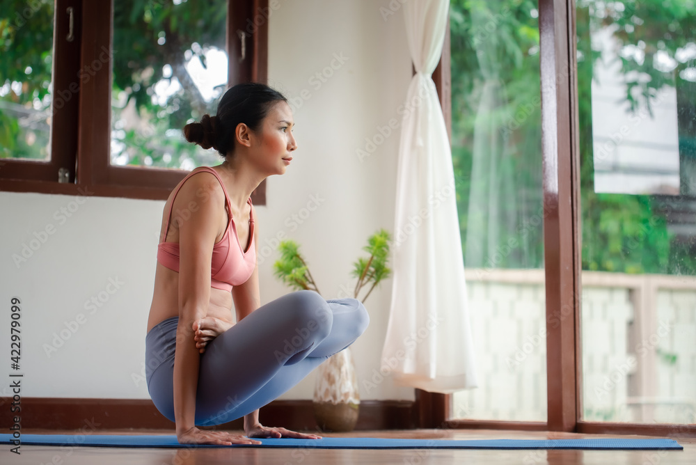 Attractive Asian woman practicing yoga in the living room at home. Attractive Asian woman practicing yoga in the living room at home.