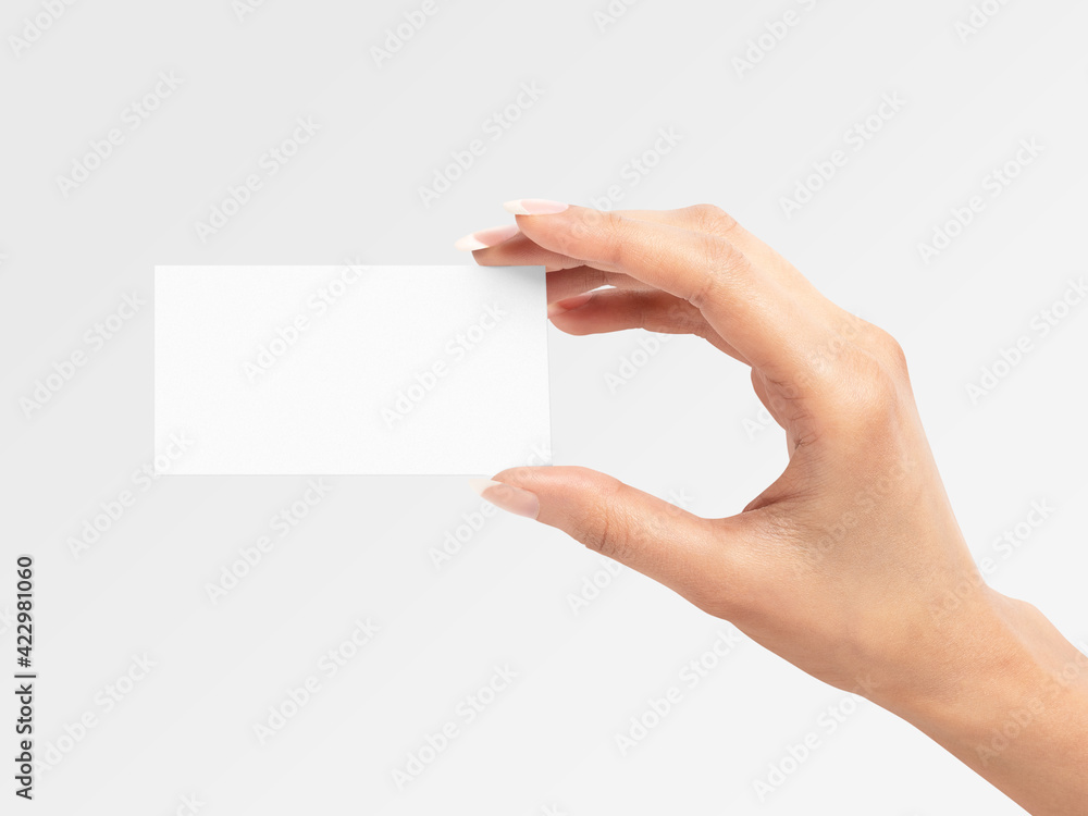 Obraz premium Beautiful female hand holding plain white business card on isolated background