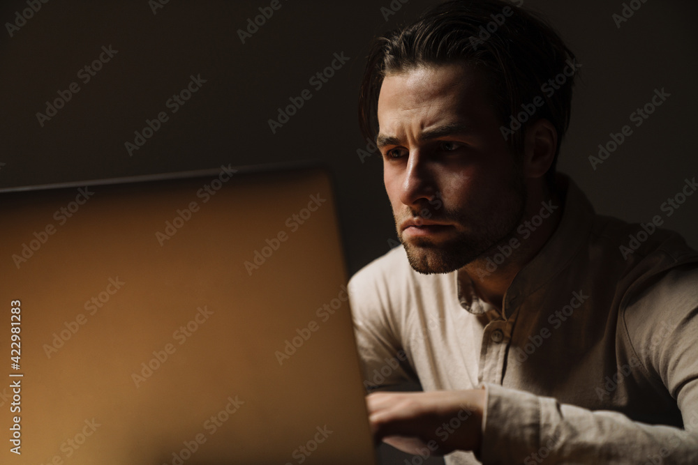Serious pensive brunette businessman working on laptop