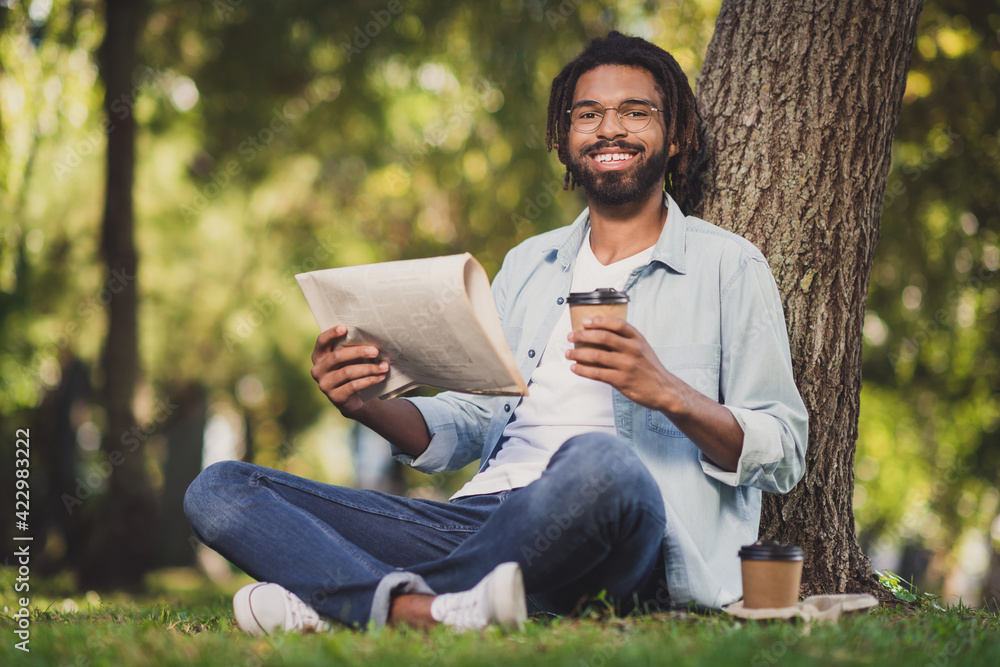 Photo portrait of man in glasses smiling sitting in green park under tree drinking cofee reading newspaper Photo portrait of man in glasses smiling sitting in green park under tree drinking cofee reading newspaper