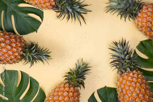 Fototapeta Naklejka Na Ścianę i Meble -  Top view of fresh pineapple with tropical leaves on yellow background.