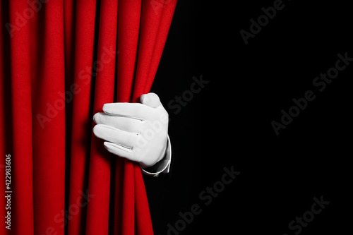 Person opening red front curtains on black background, closeup. Space for text