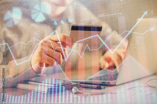 Double exposure of man hands holding a credit card and Forex graph drawing. Stock trading and digital fintech in Internet E-commerce concept.