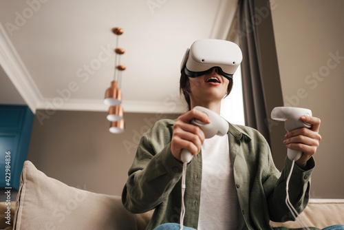 Excite white woman playing online game with vr glasses and controllers photo