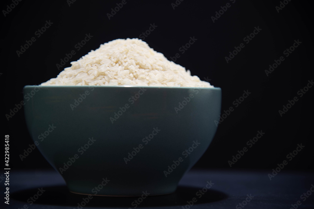 porcelain pan with raw white rice on black background porcelain pan with raw white rice on black background