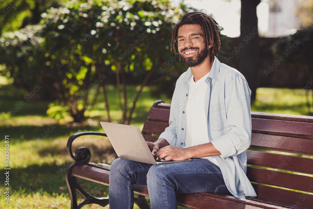 Photo of cheerful attractive afro american man sit bench good mood wear glasses in park outside outdoors