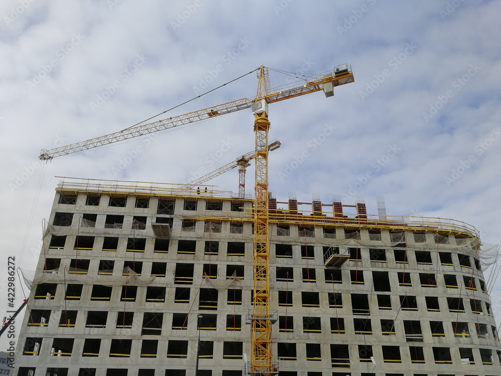 A modern apartment building is being built with a crane