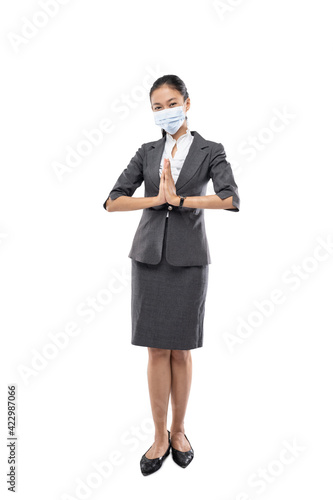 standing business woman wearing health mask with hand welcoming guests and white wall background