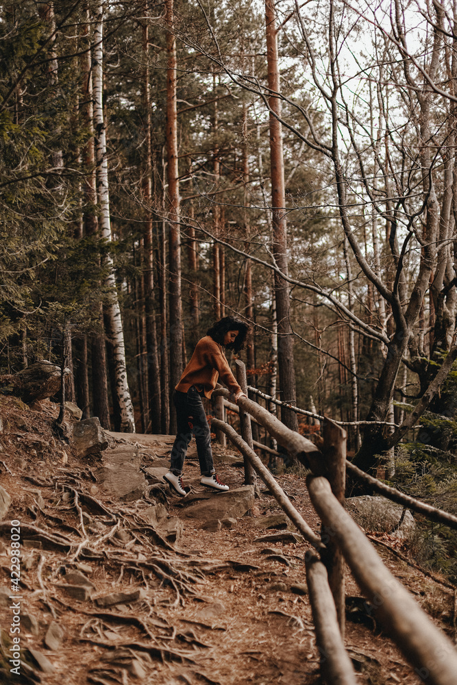curly girl tourist stands on the path and holding onto a wooden fence in the forest in the Carpathian mountains in Ukraine curly girl tourist stands on the path and holding onto a wooden fence in the forest in the Carpathian mountains in Ukraine