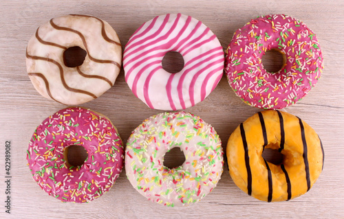 Sweet round assorted donuts on a wooden background. High-calorie bright sweets