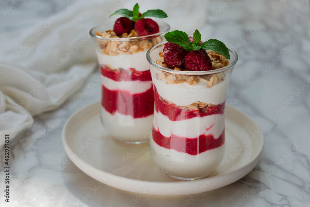Cheesecake in a glass with fresh raspberries and cream cheese on a marble table. Healthy homemade organic dessert. Cheesecake in a glass with fresh raspberries and cream cheese on a marble table. Healthy homemade organic dessert.
