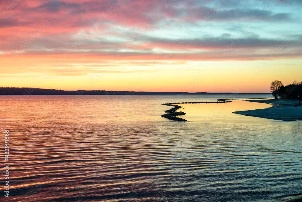 Beautiful sunset over the sea on a frosty weather. Colorful sky with clouds reflected in the water.