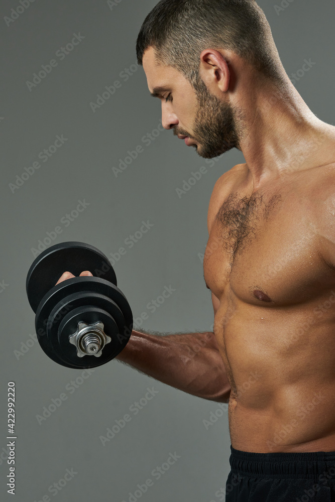 Adorable athlete man toning muscles in room indoors
