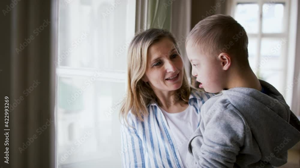 Single mother with down syndrome child at home, talking by window. Single mother with down syndrome child at home, talking by window.