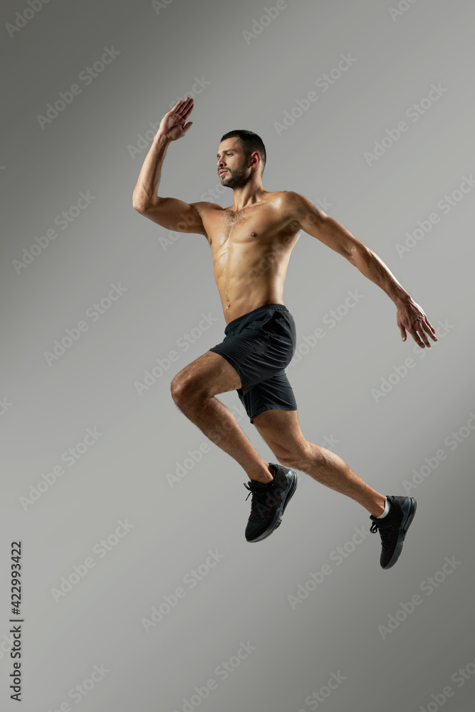 Strong handsome sportsman in sportswear warming up in the room indoors Strong handsome sportsman in sportswear warming up in the room indoors