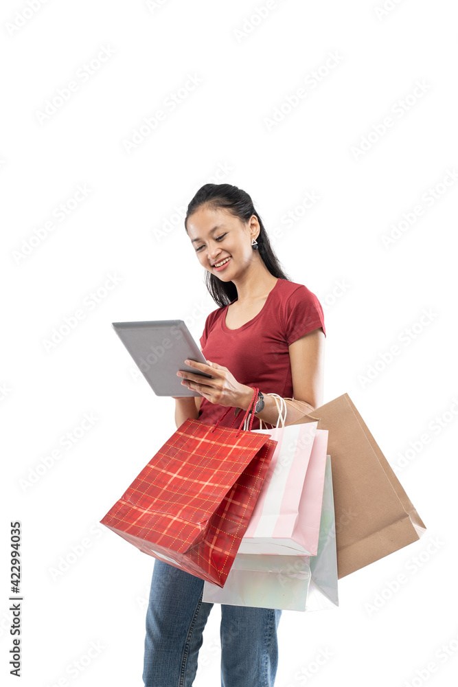 Beautiful woman holding a shopping bag and looking the tablet with smile expression on white background Beautiful woman holding a shopping bag and looking the tablet with smile expression on white background