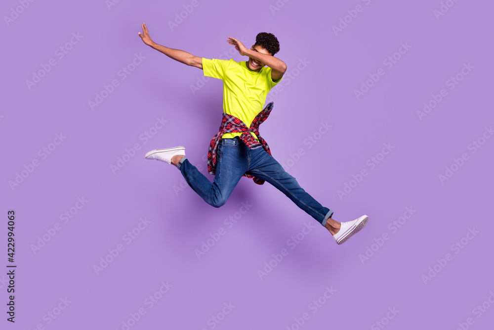 Full size photo of young handsome cheerful smiling positive afro man jumping show dab isolated on purple color background