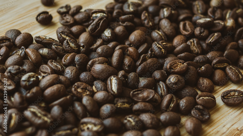 Fototapeta premium Freshly roasted aromatic coffee beans for filter coffee makers are scattered on a wooden table