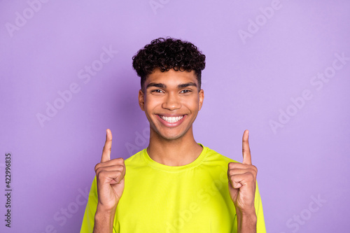 Photo of young black man happy positive smile indicate finger empty space ad promo select isolated over purple color background