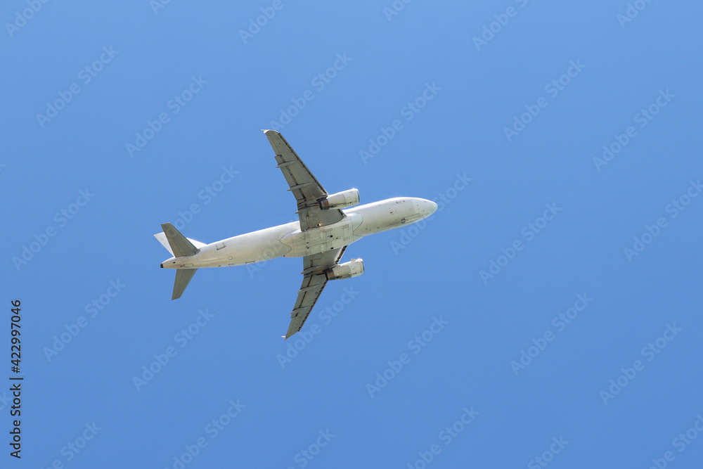 Airplane flying in the clear blue sky, bottom view. Commercial plane taking off and gaining altitude Airplane flying in the clear blue sky, bottom view. Commercial plane taking off and gaining altitude