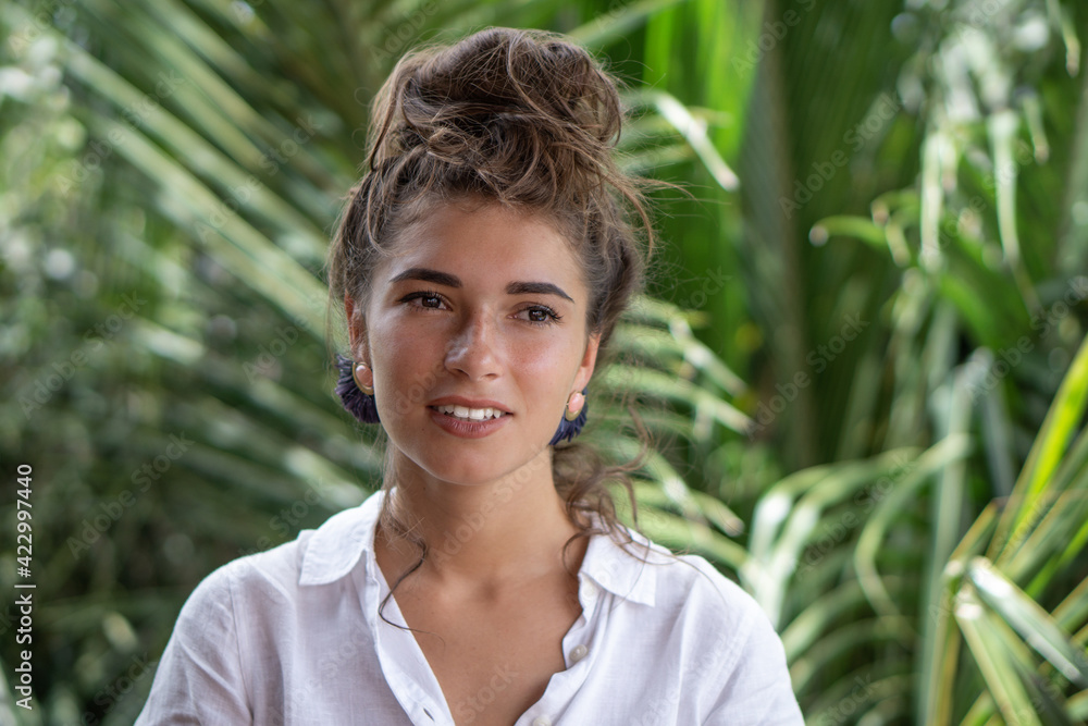 Portrait of young beautiful woman close up in white shirt with white teeth smile and palm trees view on background Portrait of young beautiful woman close up in white shirt with white teeth smile and palm trees view on background