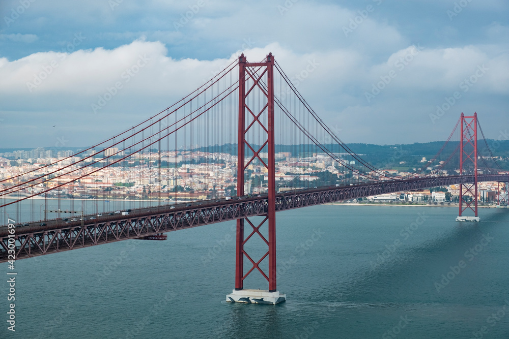 Fototapeta premium Modern bridge On April 25 in Lisbon, the capital of Portugal, in cloudy cloudy weather, cars drive on the gigantic bridge across the strait.