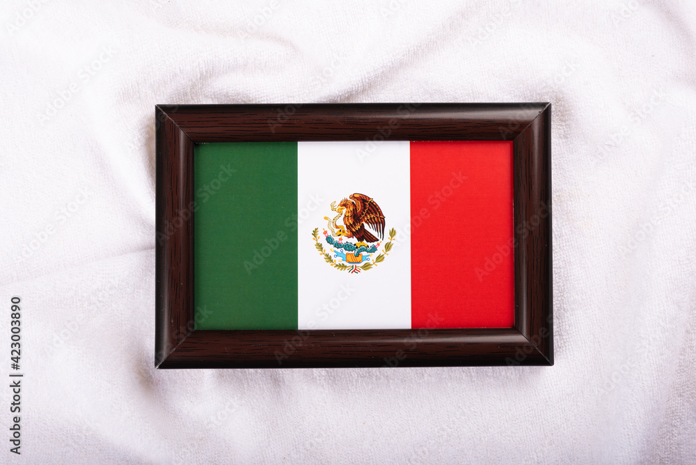 Fototapeta premium Mexico flag in a realistic frame on white cloth background flat lay photo