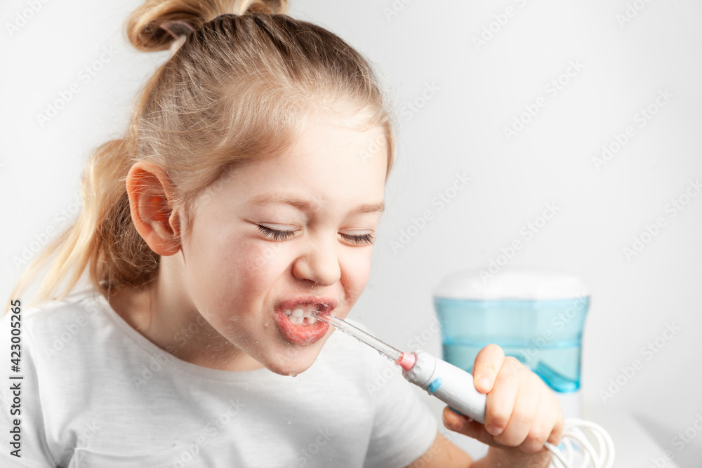 Water flosser. Little girl child brushes teeth. Water jet from the irrigator. Water flosser. Little girl child brushes teeth. Water jet from the irrigator.