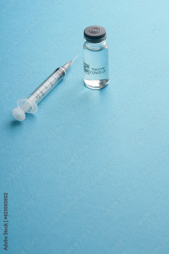 bottle of covid19 vaccine and syringe against blue background bottle of covid19 vaccine and syringe against blue background