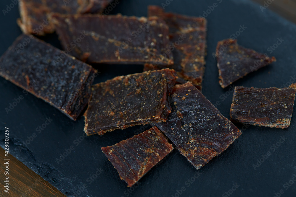 Beef jerky on black stone surface. Dried meat. Beef jerky on black stone surface. Dried meat.