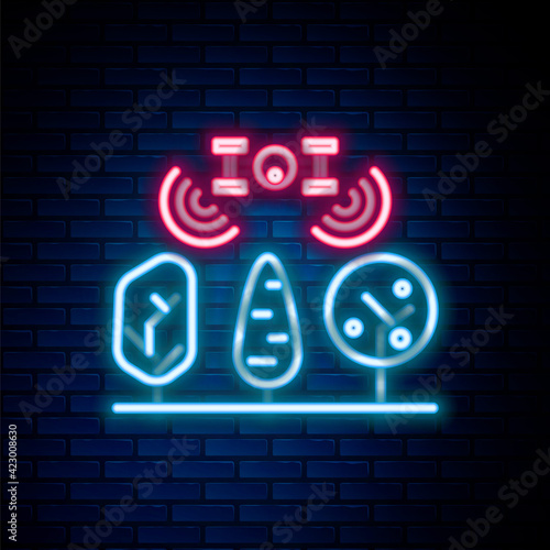 Glowing neon line Smart farm with drone control and tree icon isolated on brick wall background. Innovation technology for agricultural company. Colorful outline concept. Vector