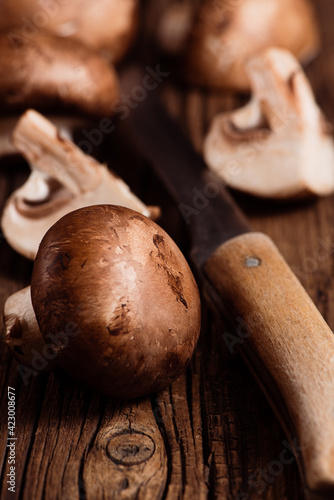 Obraz na płótnie Fresh brown champignon mushrooms and knife on wooden table. Closeup of cremini mushrooms. Selective focus. w salonie