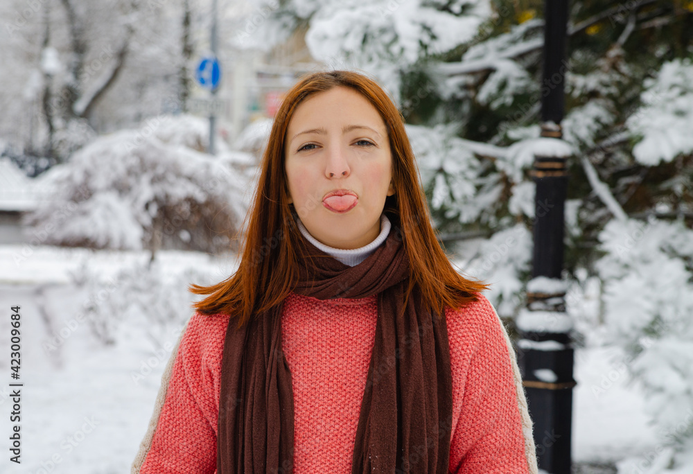 A red-haired girl in a red sweater against the snow. A walk in winter. Playing with snow A red-haired girl in a red sweater against the snow. A walk in winter. Playing with snow