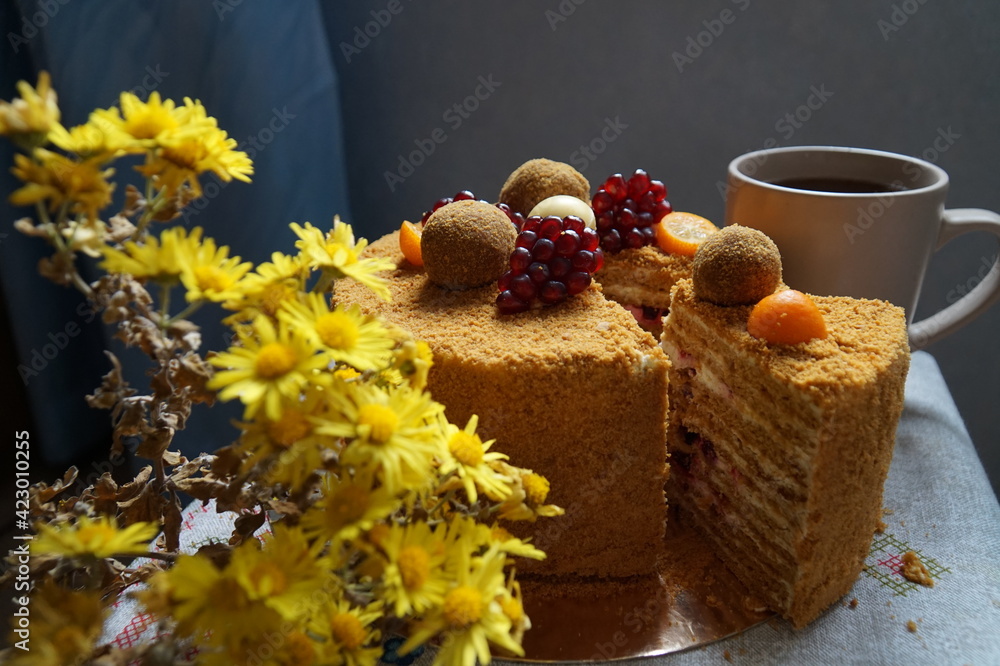 Naklejka premium Delicious honey cake decorated with mantarines and pomegranate stands on the table