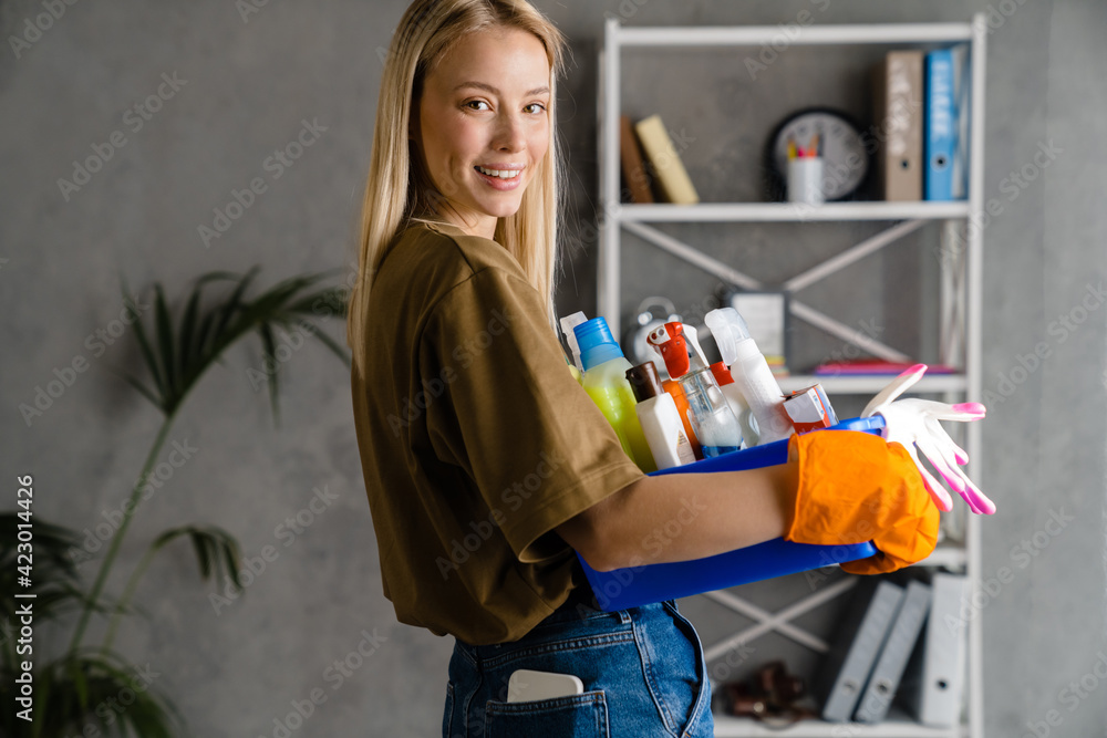 Happy european woman in gloves posing with cleaning product at home