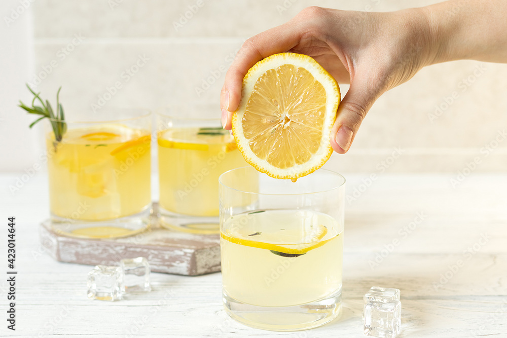 Female hand squeezes lemon into water, summer vitamin drink Female hand squeezes lemon into water, summer vitamin drink