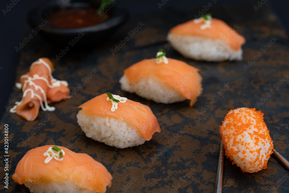 Sushi rolls nigiri with salmon and salmon eggs in a stone and black background Sushi rolls nigiri with salmon and salmon eggs in a stone and black background