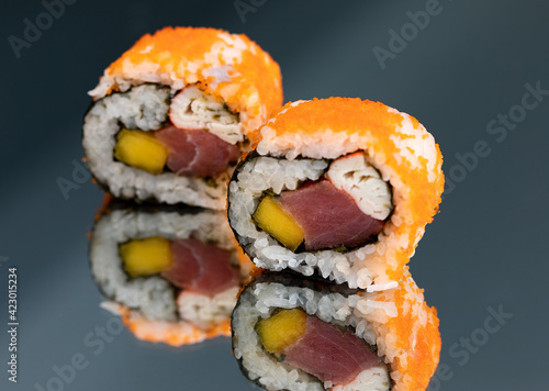 Sushi rolls with salmon avocado tuna and mango in a black background