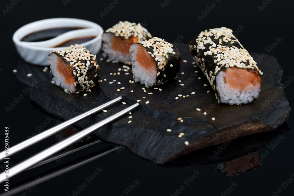 sushi roll with salmon and tuna with sesame and soy sauce y a black stone background sushi roll with salmon and tuna with sesame and soy sauce y a black stone background
