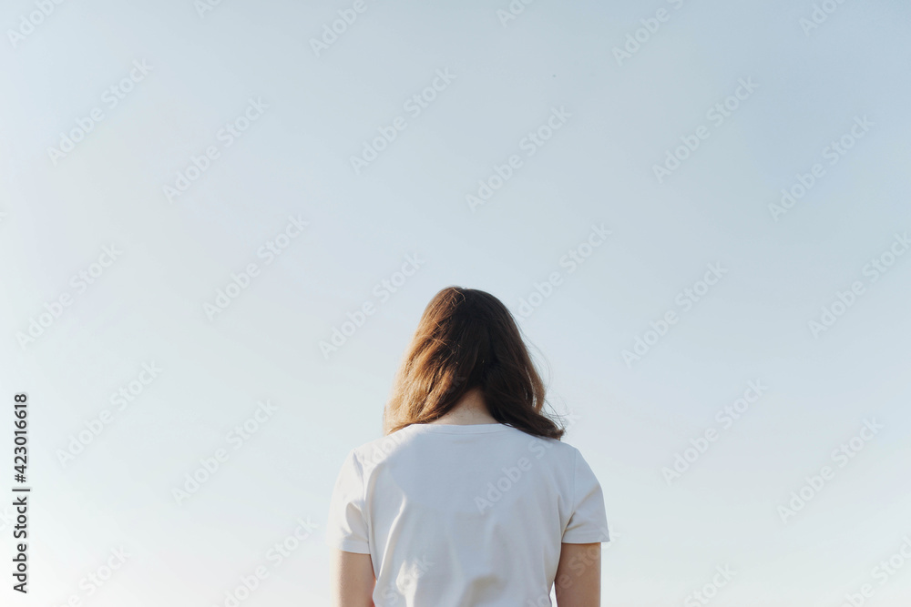 Dreamy portrait of a young brunette woman at blue sky background Dreamy portrait of a young brunette woman at blue sky background