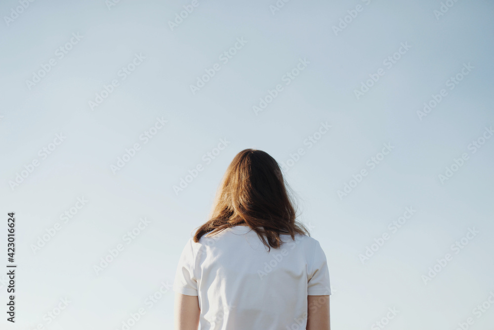 Dreamy portrait of a young brunette woman at blue sky background Dreamy portrait of a young brunette woman at blue sky background