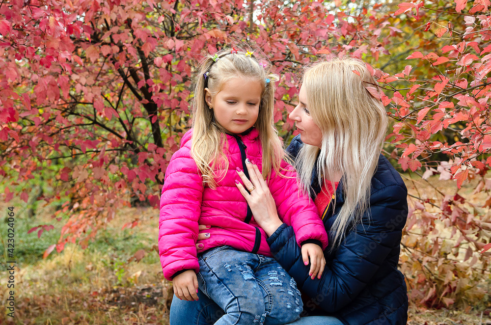 A little girl walks and plays with her mother in the park. Autumn landscape with golden leaves A little girl walks and plays with her mother in the park. Autumn landscape with golden leaves